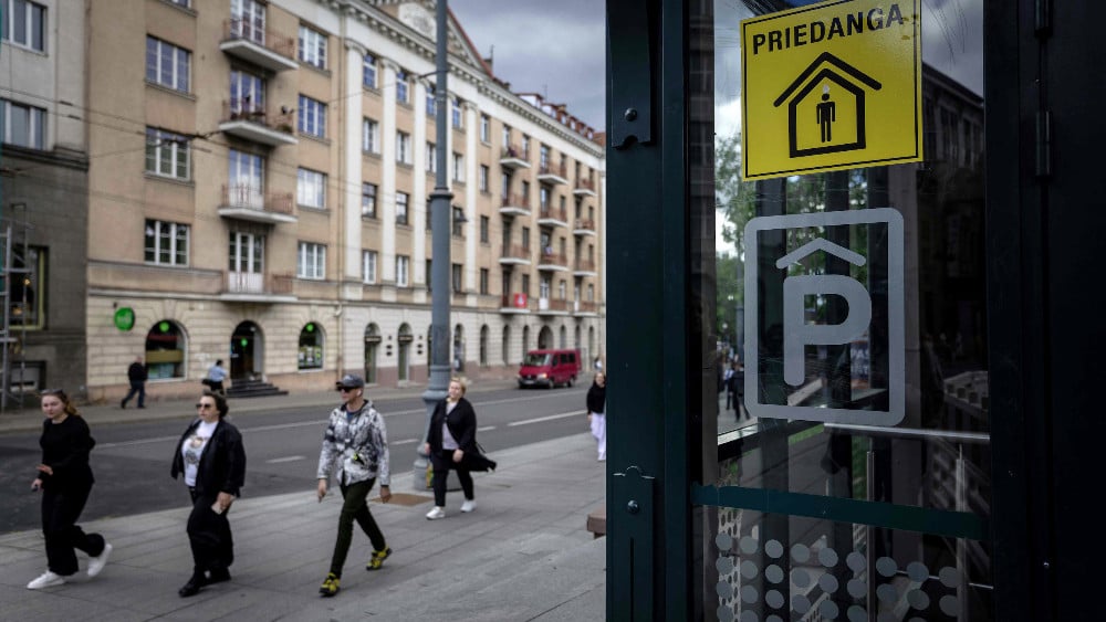 People pass the entrance to an underground car park marked as a shelter with a yellow sticker reading 'Priedanga' (Shelter) on Gediminas Prospect in central Vilnius on May 28, 2026. (AFP)