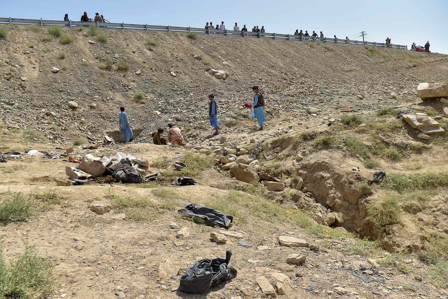 Afghans stand at the accident site, after a passenger bus overturned on the Kabul-Kandahar highway, on the outskirts of Maidan Wardak province on August 27, 2025. (AFP)