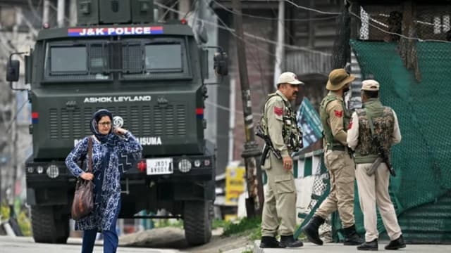FILE: Indian policemen stand guard as a woman walks along a street in Srinagar. (Photo: Sajjad Hussain/AFP)