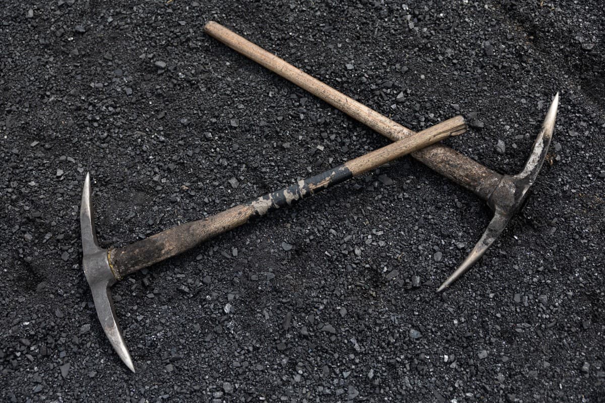 Pickaxes lie on a bed of coal fragments near the entrance of the Golfview informal coal mine in Ermelo on September 25, 2025.