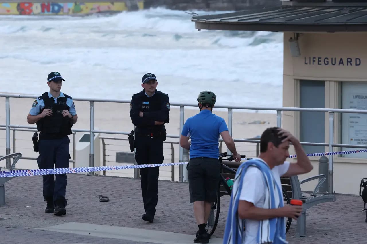 Police officers assist a visitor at the scene of a shooting at Bondi Beach in Sydney on December 15, 2025 (AFP)