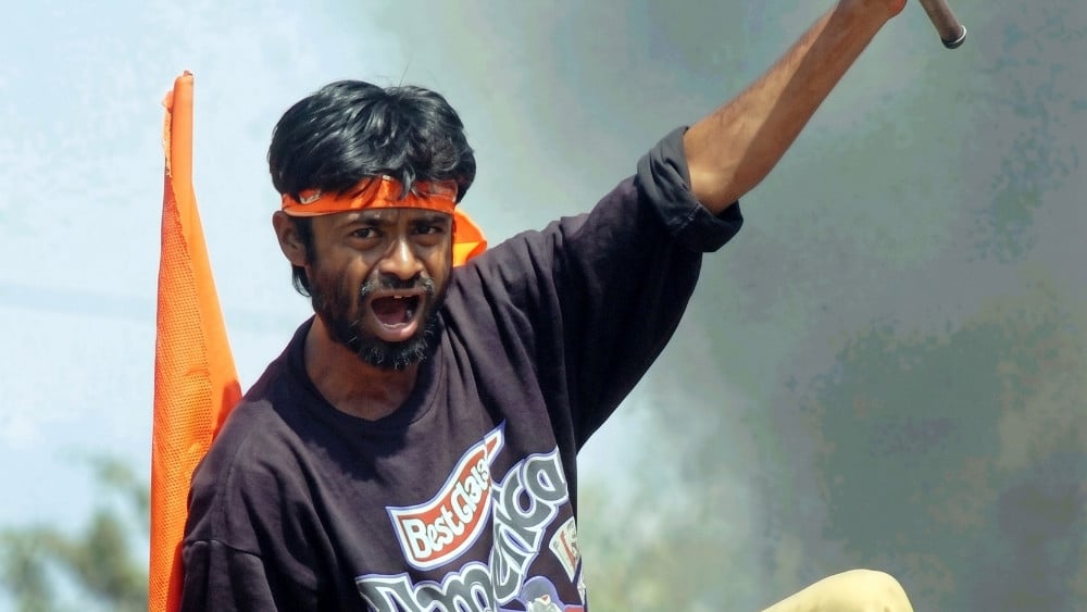 A Bajranj Dal activists climbs on top of a billboard as he shouts slogans against Muslims, burning shops and attacked homes at Sahapur in Ahmedabad. (AFP)