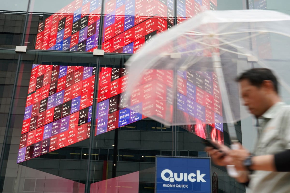 A man walks next to an electronic quotation board displaying the Nikkei 225 stock prices on the Tokyo Stock Exchange in Tokyo on June 18, 2026. (Photo by Kazuhiro NOGI / AFP)