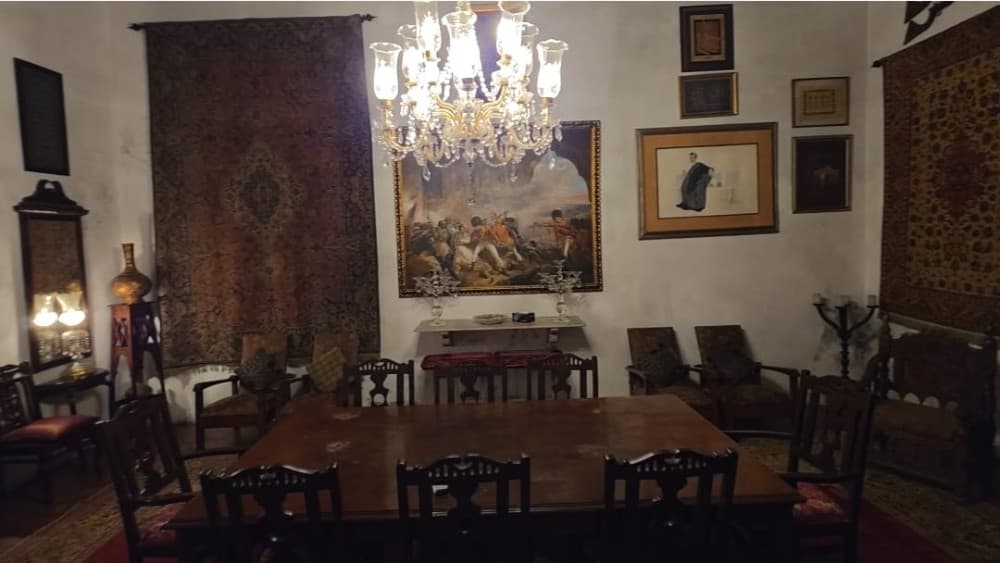 The dining room at Haveli Barood Khana, with walls adorned with paintings, textiles, and family heirlooms, including a historic carpet associated with the 1940 Lahore Resolution. (Photo by Faraz Saeed)