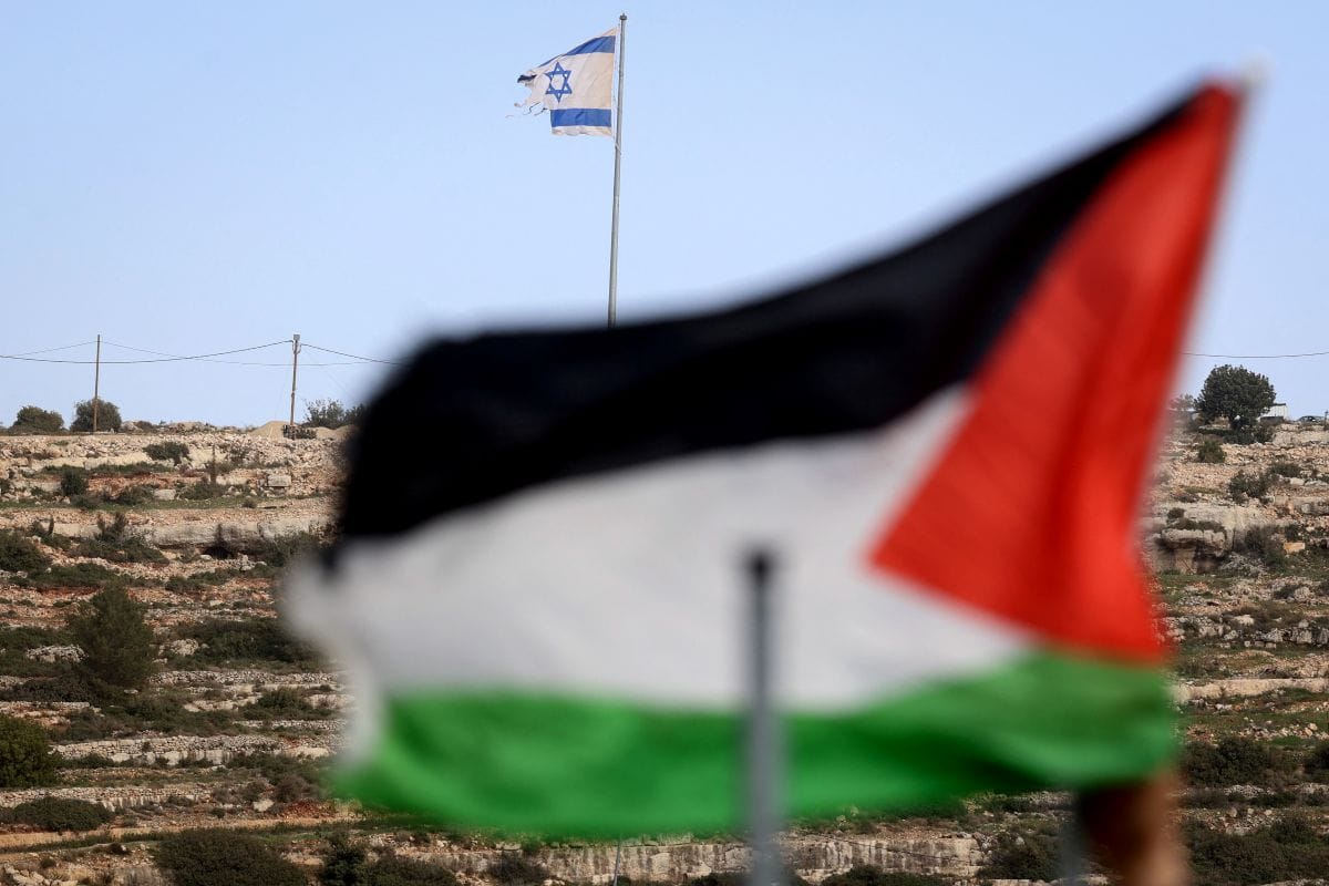 This picture taken from Umm Safa village, north of Ramallah in the occupied West Bank, shows a Palestinian flag (foreground) and Israeli flag fluttering on a hilltop overlooking the village on February 16, 2026. (AFP)