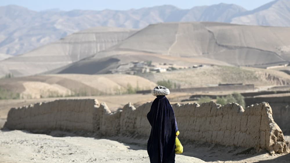 An Afghan burqa-clad woman walks along a road in Argo district of Afghanistan's Badakhshan province on September 15, 2026. (Photo by Omer ABRAR / AFP)