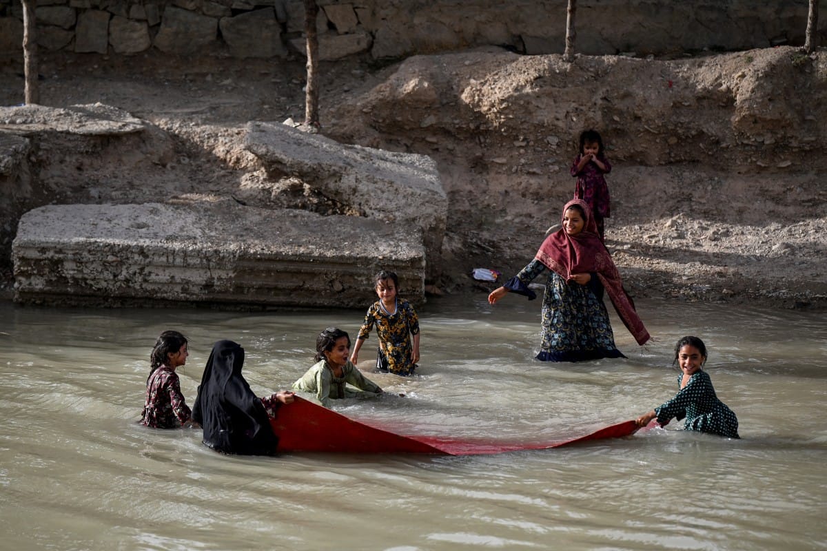 Afghan girls wash a carpet along a canal in a village in the 9th district of Kandahar on June 16, 2026. (Photo by Sanaullah SEIAM / AFP)