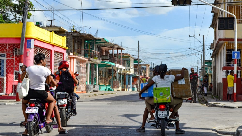 Motorcyclists ride through an intersection with nonfunctioning traffic lights during a power outage in Guantanamo, Cuba, on August 3, 2026, highlighting the transportation and infrastructure challenges caused by the blackout.