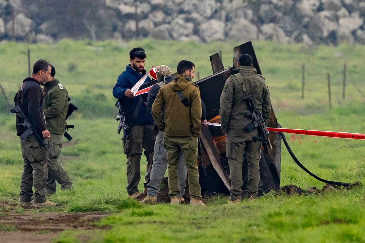 Israeli security personnel secure an area around a rocket partly buried in a field in the Israeli-annexed Golan Heights on March 19, 2026. (AFP)