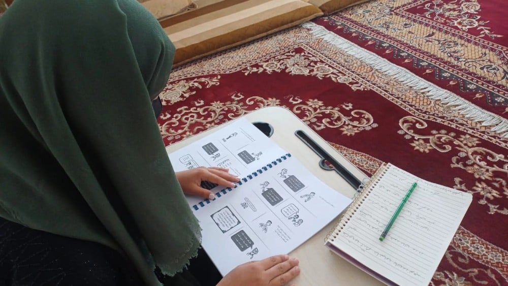 Afghan woman following a radio-based literacy program ( Photo by UNAMA / Hashmatullah Elkhani)