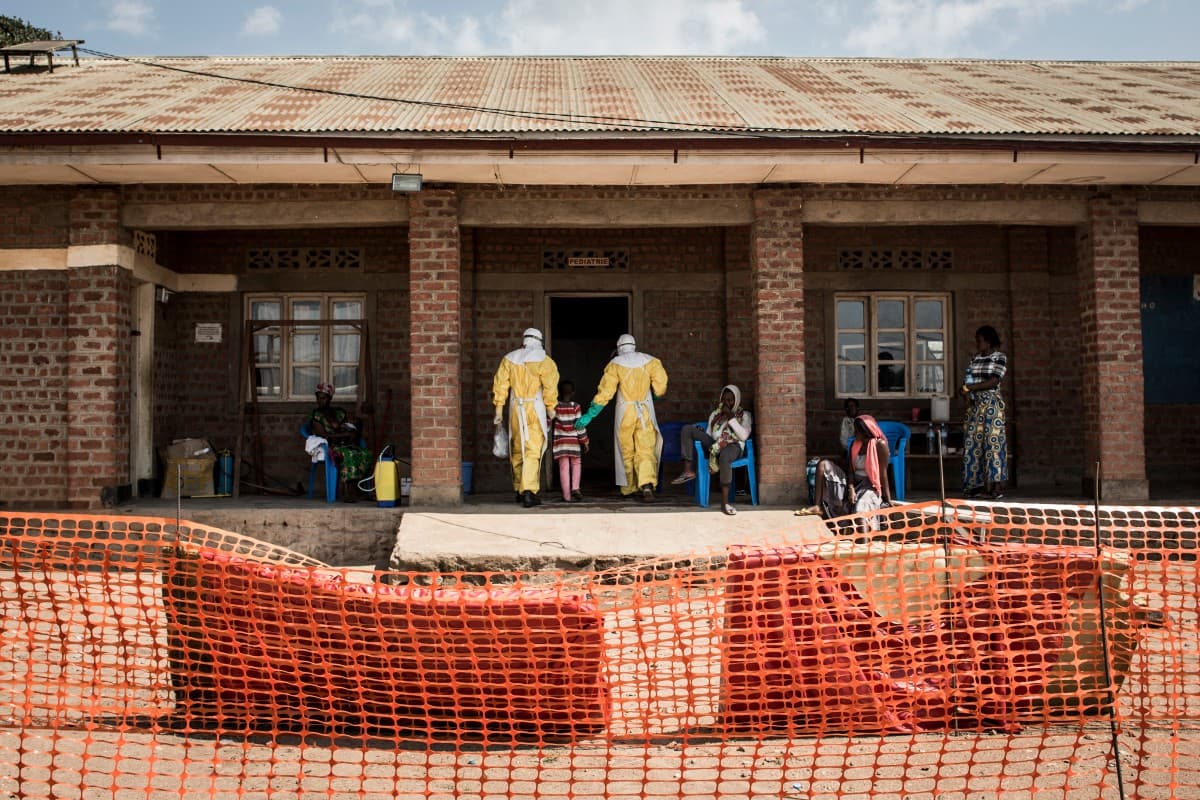Medical workers lead a young girl with suspected Ebola into the unconfirmed Ebola patients ward run by The Alliance for International Medical Action (ALIMA) on August 12, 2018 in Beni, northeastern DRC.