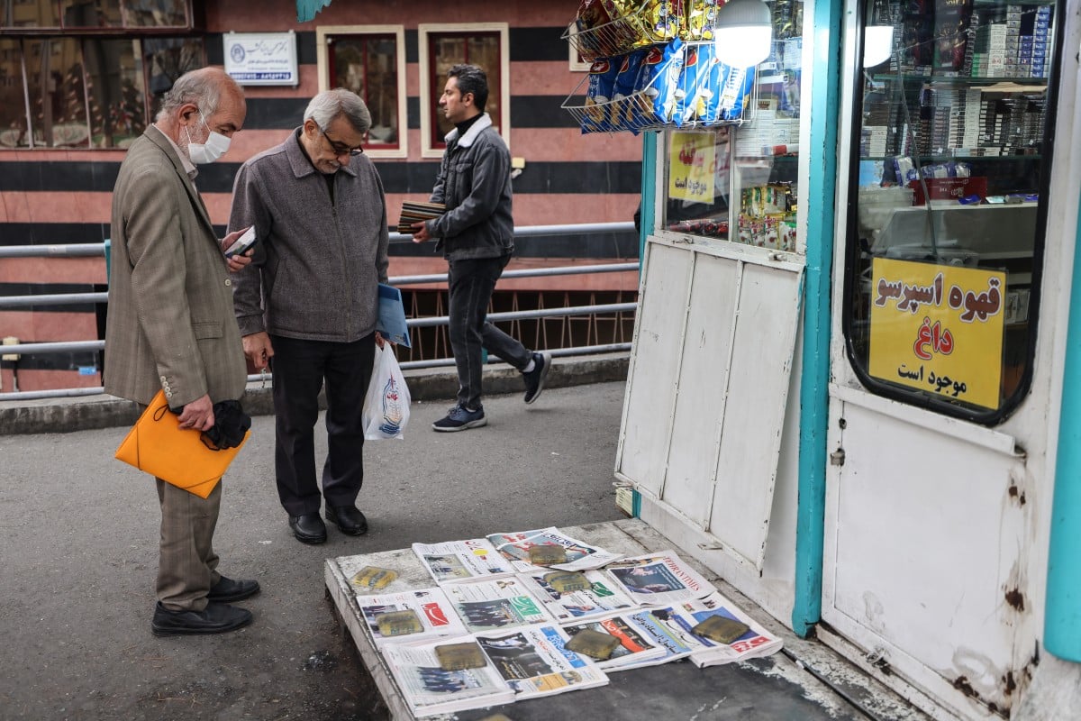 Men look at Iranian daily newspapers reporting on the first round of talks between Iran and the United States at a kiosk in Tehran. (AFP)