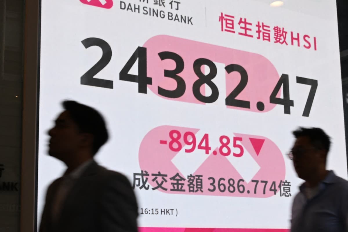 Pedestrians walk past an electronic signboard showing the closing price of the Hang Seng Index in Hong Kong on March 23, 2026 (AFP)