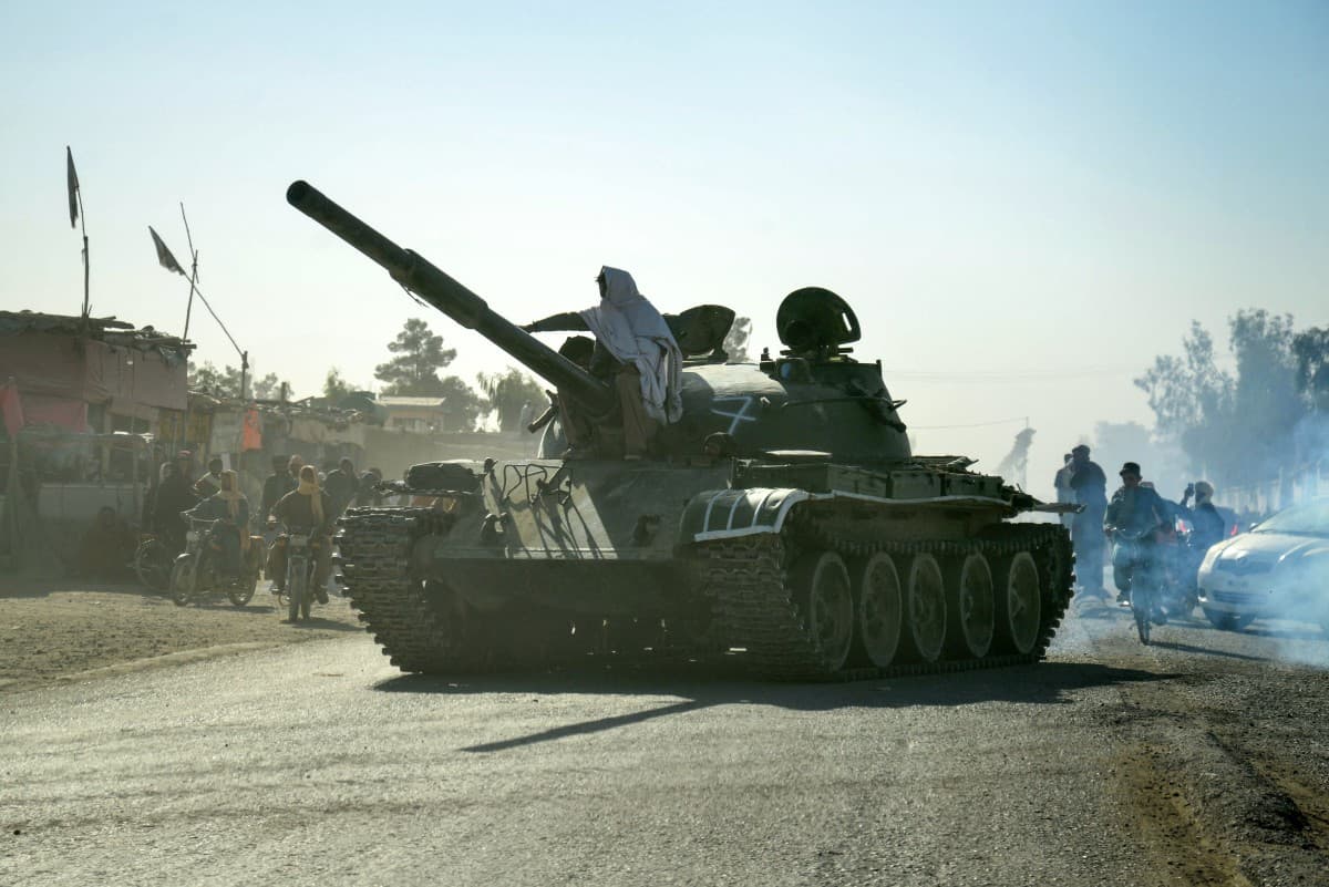 Taliban security personnel on a Soviet-era tank are followed by motorcyclists as they ride towards the border, as clashes take place between Taliban security personnel and Pakistani border forces, in the Spin Boldak district of Kandahar Province on Octobe