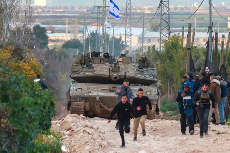 Palestinian children and journalists disperse as Israeli tanks enter the Jenin camp for Palestinian refugees in the occupied West Bank. (Jaafar Ashtiyeh/AFP)