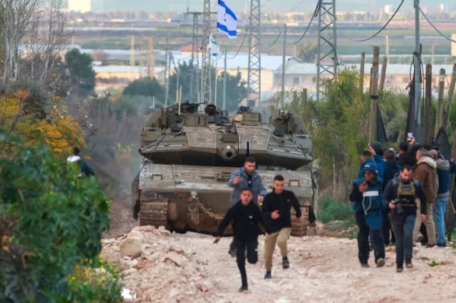 Palestinian children and journalists disperse as Israeli tanks enter the Jenin camp for Palestinian refugees in the occupied West Bank. (Jaafar Ashtiyeh/AFP)