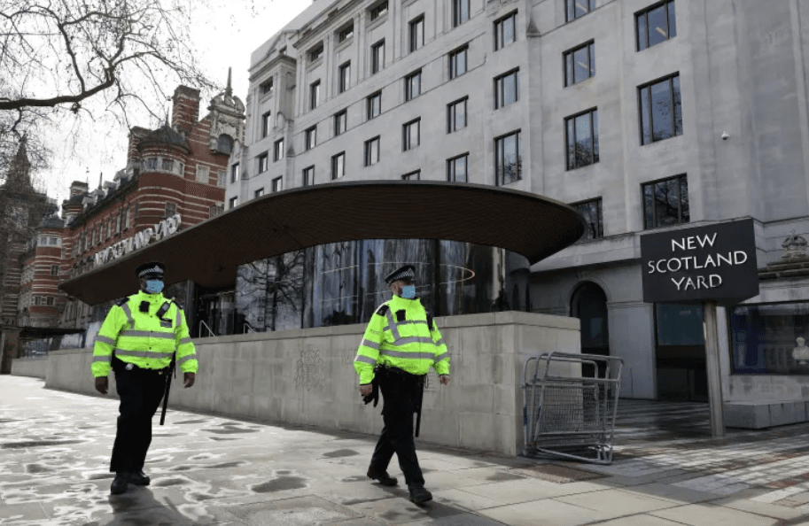 Two Police officers walking outside New Scotland Yard in London.