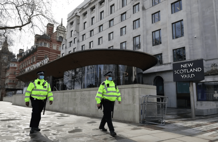 Two Police officers walking outside New Scotland Yard in London.