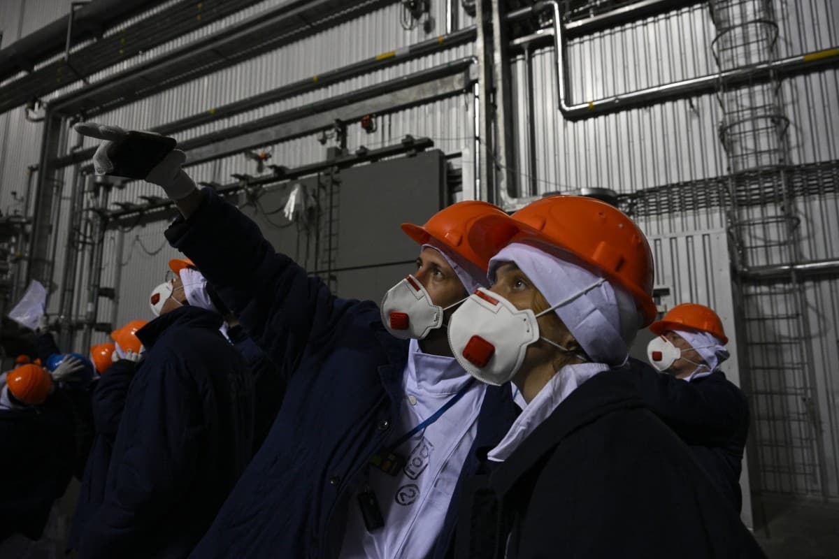 Representatives of Greenpeace and media stand in front of the sarcophagus covering the destroyed fourth reactor under the New Safe Confinement (NSC), at the Chornobyl Nuclear Power Plant on April 9, 2026. (AFP)