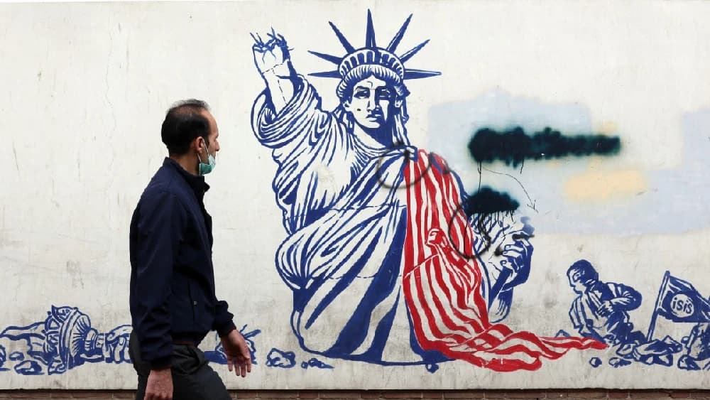 A man walks past a mural depicting the US Statue of Liberty with the torch-bearing arm broken, painted on the outer walls of the former US embassy, in Tehran on February 6, 2026. (Photo: AFP/File)