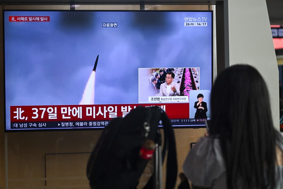 A woman watches a television screen showing a news broadcast with file footage of a North Korean missile test, at a train station in Seoul on May 26, 2026. North Korea launched an "unidentified projectile" into the Yellow Sea off its west coast on May 26,