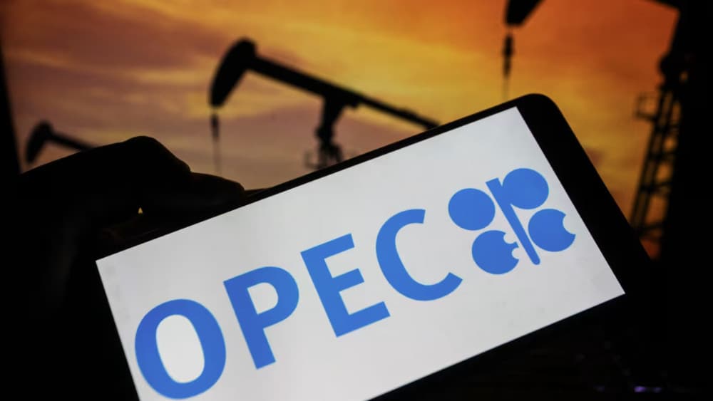A smartphone displaying the OPEC logo is photographed in front of oil pumpjacks operating at sunset, illustrating the global petroleum industry and crude oil production in Tunis,Tunisia on June 28, 2026. (AFP)