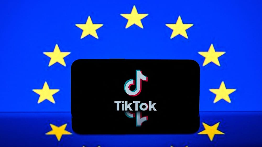 This photograph shows a screen displaying the Tiktok social media platform's logo and the European flag on April 26, 2023 in Toulouse, southwestern France. The EU said on February 6, 2026, that it had told TikTok it needs to change its "addictive design"