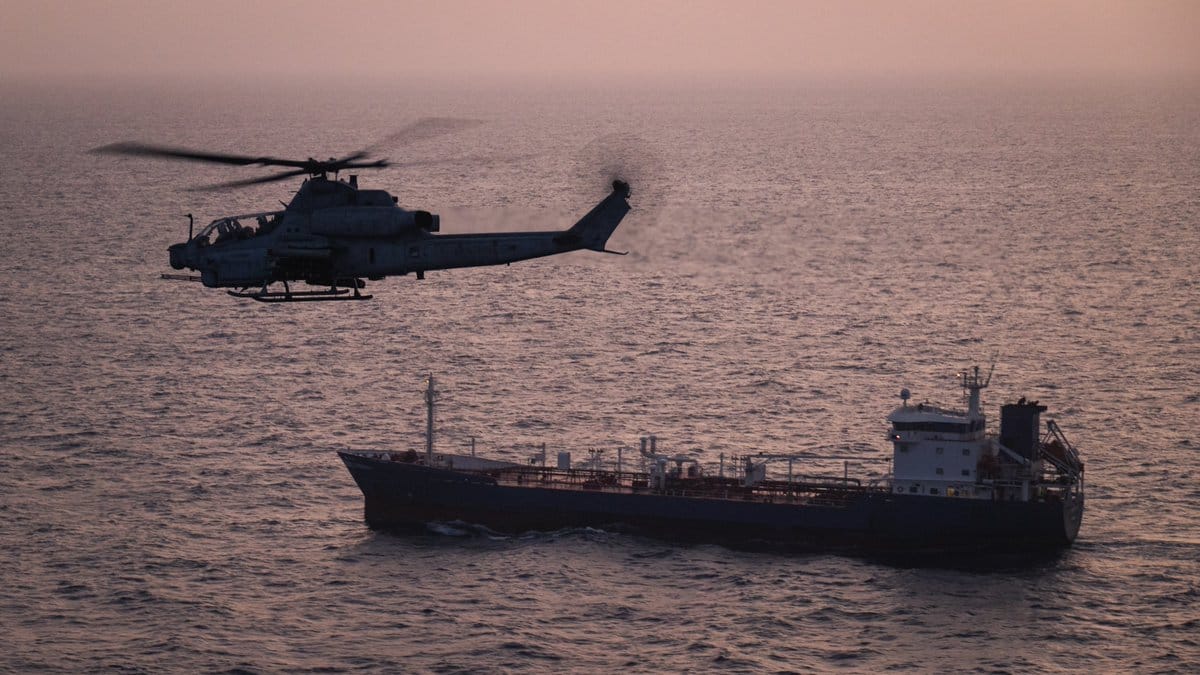 A US Marine Corps AH-1Z Viper attack helicopter patrols near a commercial vessel transiting regional waters as American forces enforce the maritime blockade against Iran. (File photo: US CENTCOM/X)