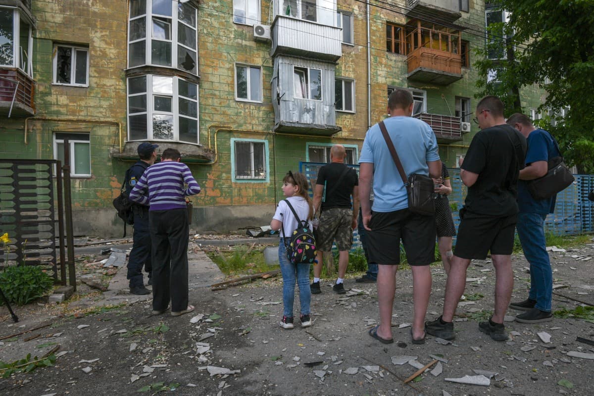 Local residents stand next to debris and a damaged residential building following an air attack in Dnipro on May 21, 2026, amid the Russian invasion of Ukraine. (Photo by Mykola SYNELNYKOV / AFP)