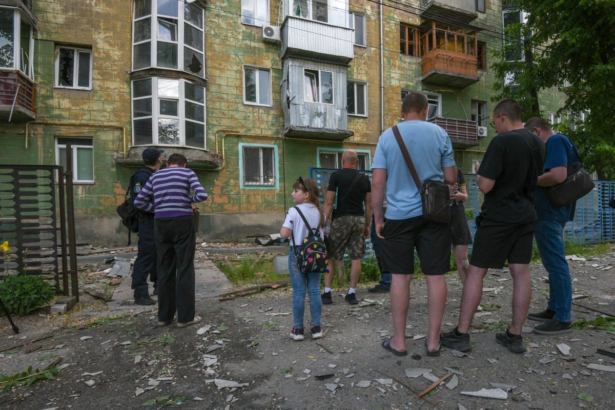 Local residents stand next to debris and a damaged residential building following an air attack in Dnipro on May 21, 2026, amid the Russian invasion of Ukraine. (Photo by Mykola SYNELNYKOV / AFP)