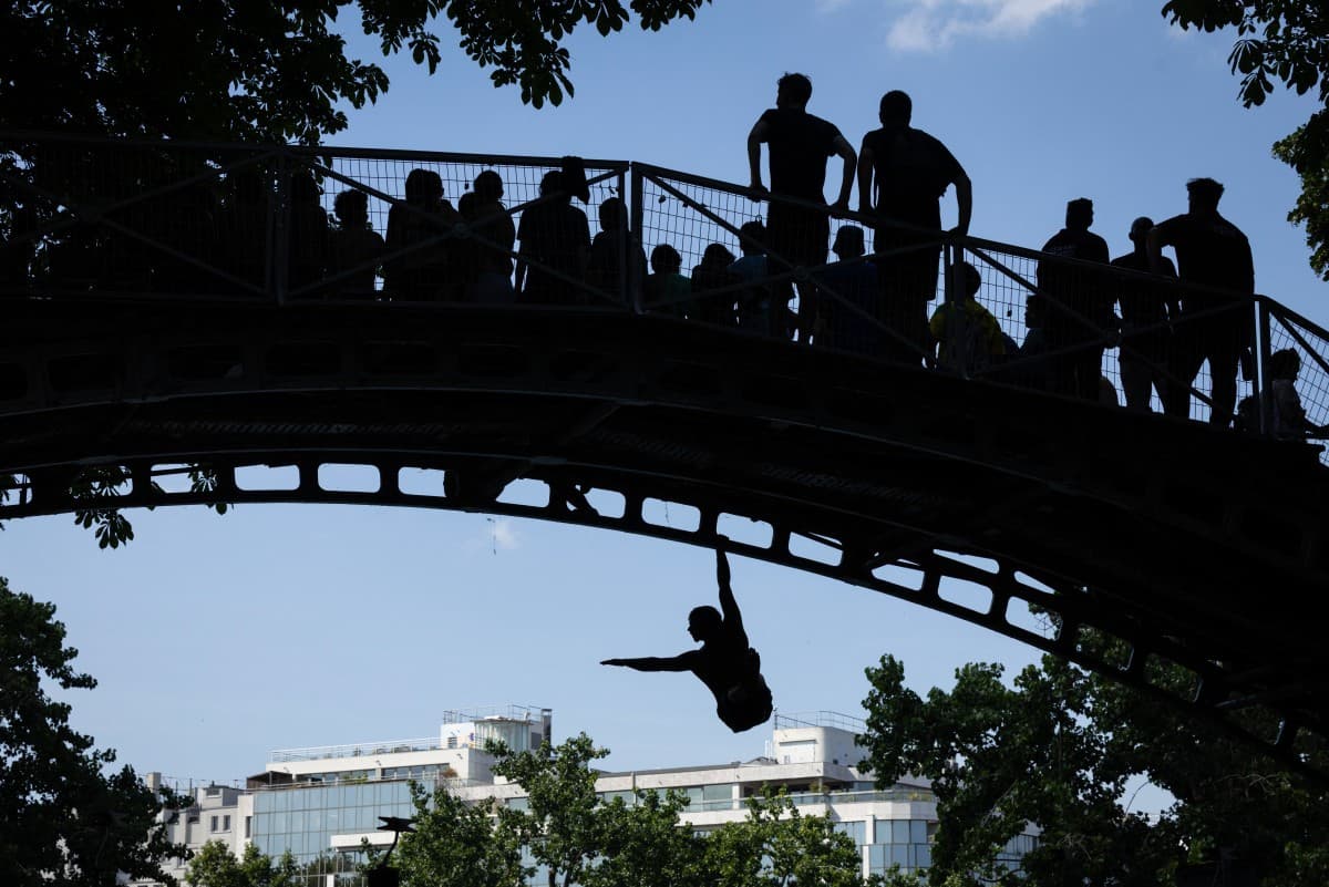 Young people jump from a bridge into the Canal Saint-Martin during a heatwave in Paris on June 22, 2026.