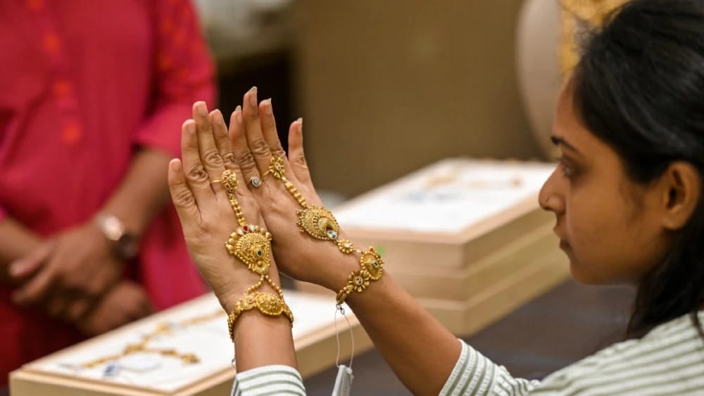 A staff member shows gold bangles at a jewellery store in Ahmedabad on May 12, 2026. (Photo: AFP)