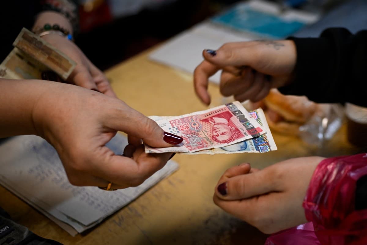 A grocery store owner returns lev banknotes to a customer in a grocery store in the village of Chuprene, northwestern Bulgaria on December 7, 2025 (AFP)