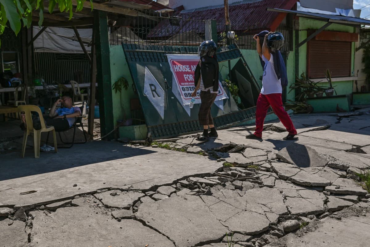 People walk along a damaged road after a 7.8 magnitude earthquake in General Santos City on June 9, 2026 (AFP)