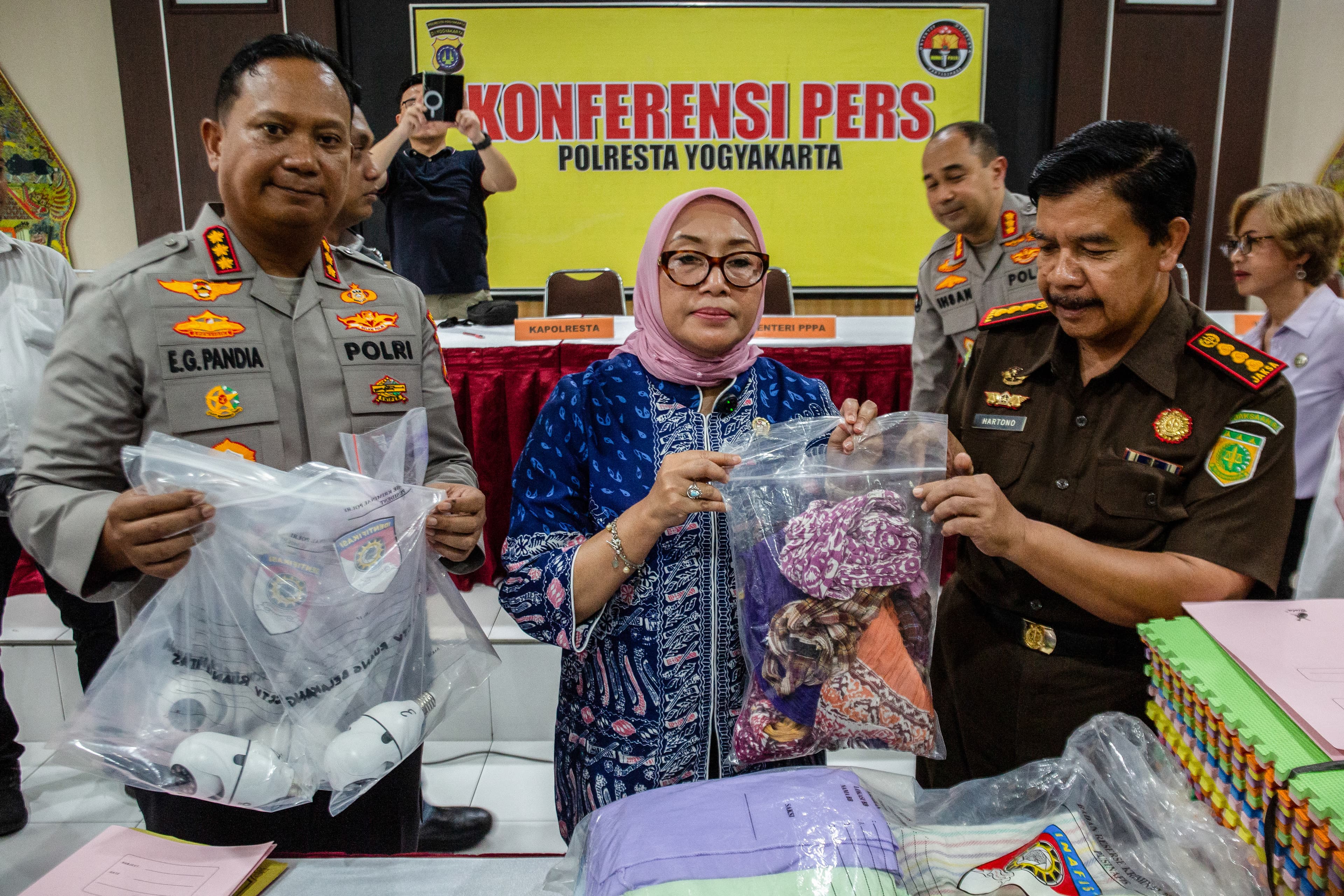 Arifah Choiri Fauzi (C), Indonesia's minister of women's empowerment and child protection, holding evidences poses for photograph during a press conference on a child abuse probe at a daycare centre, in Yogyakarta on April 27, 2026.