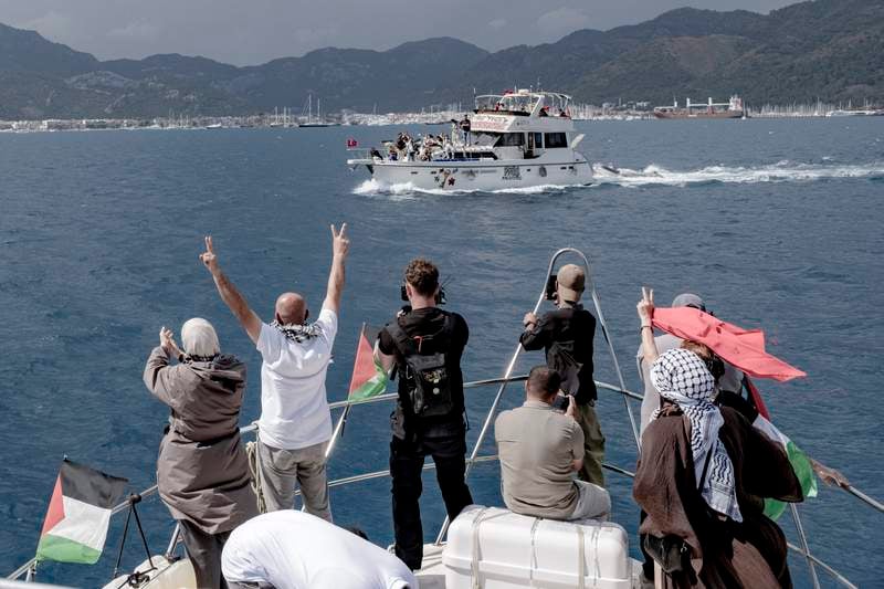 People raise V-signs and take photos from a boat decorated with Palestinian flags as another vessel displaying solidarity signs sails past near the port in Marmaris, Turkey, on May 14, 2026. (AFP)