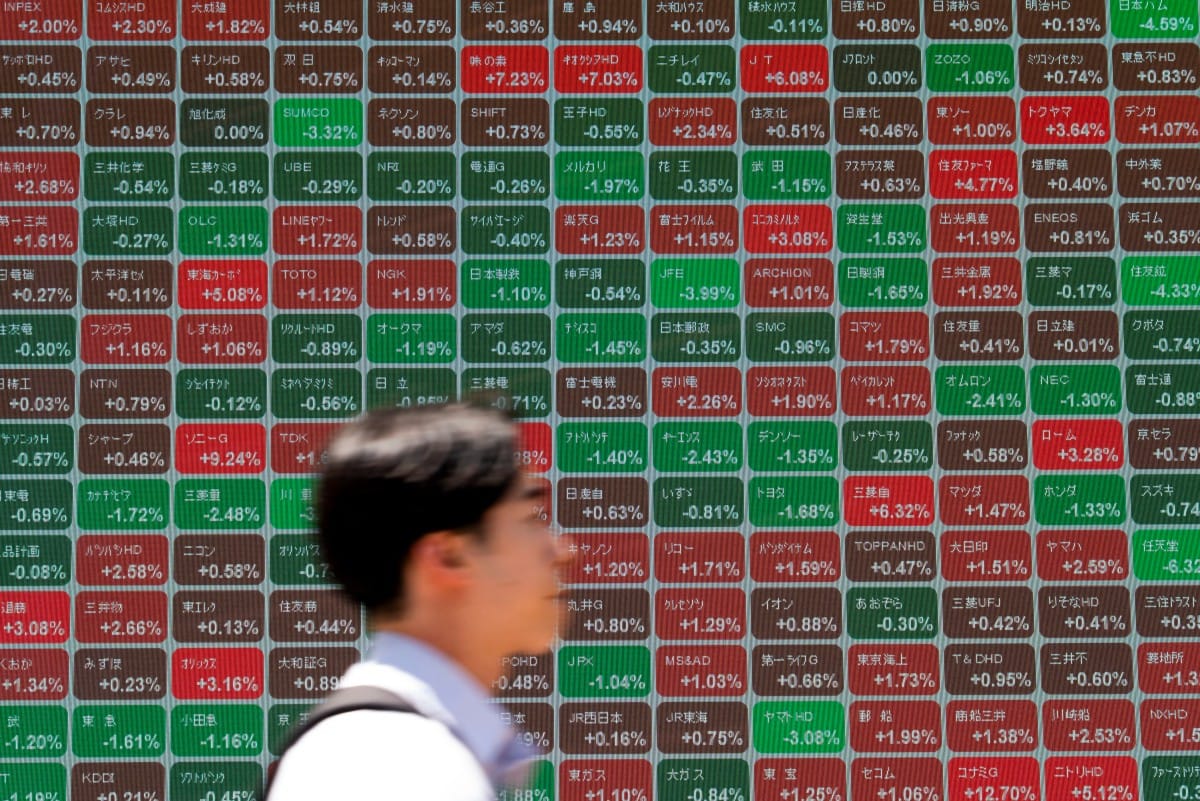 A man walks past an electronic quotation board displaying the Nikkei 225 stock prices on the Tokyo Stock Exchange along a street in Tokyo on May 11, 2026. (AFP)