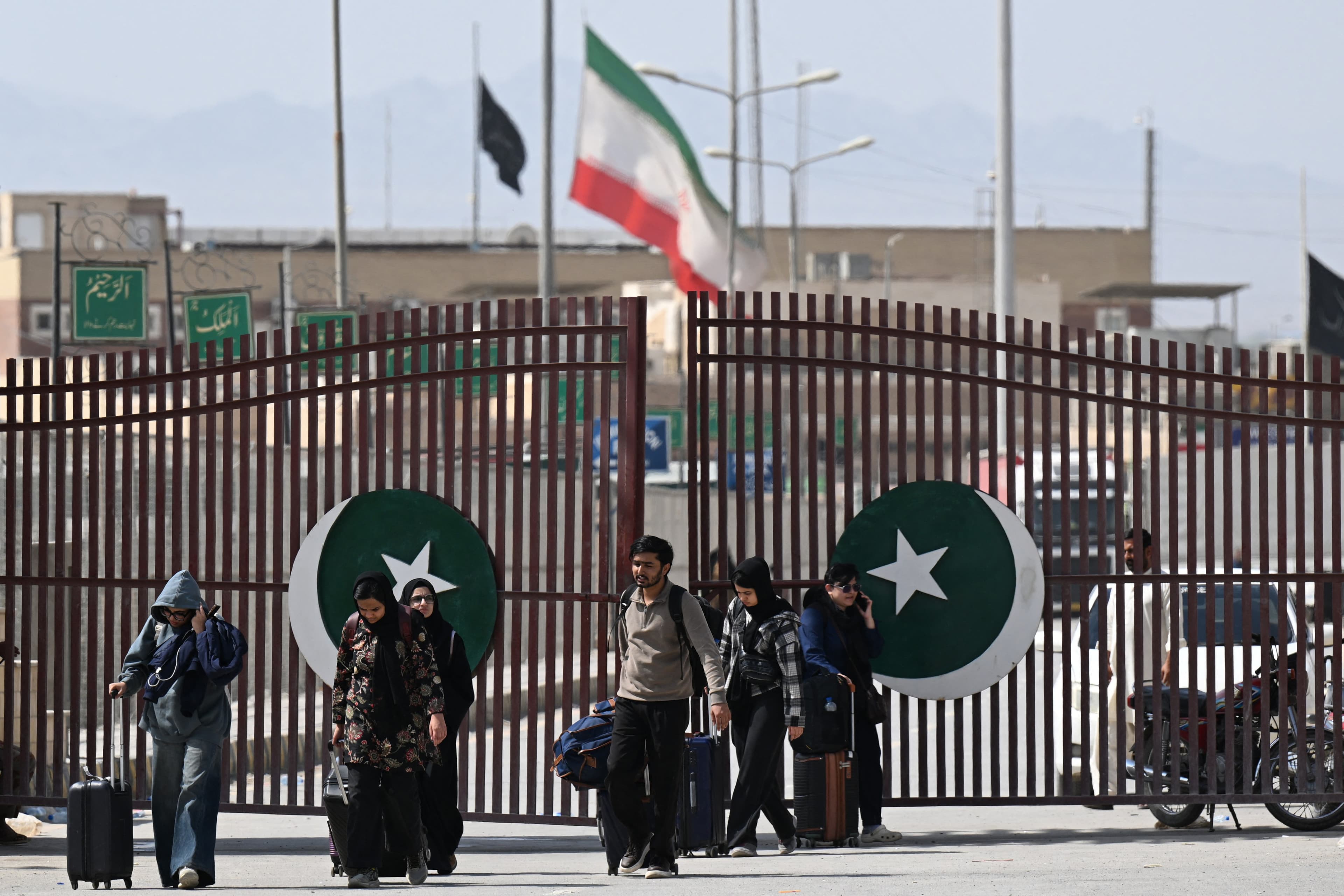 Pakistanis walk across the Taftan border as they return from Iran, in Balochistan province on March 3, 2026 amid ongoing US-Israel strikes on Iran. (AFP)