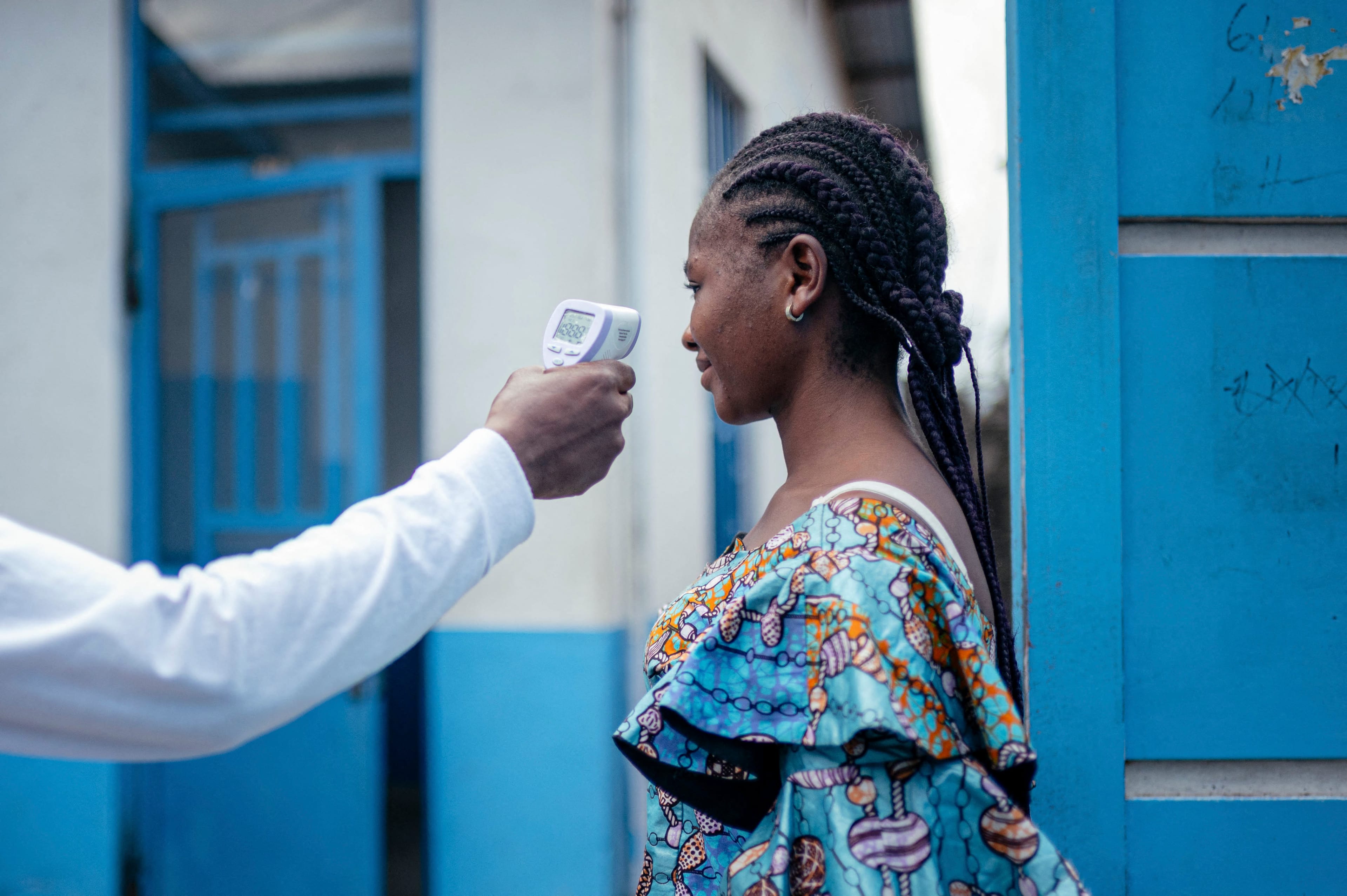 A staff member of the CBCA Virunga Hospital checks a visitor’s temperature using a a contactless infrared thermometer, before allowing her access to the hospital in Goma on May 17, 2026.