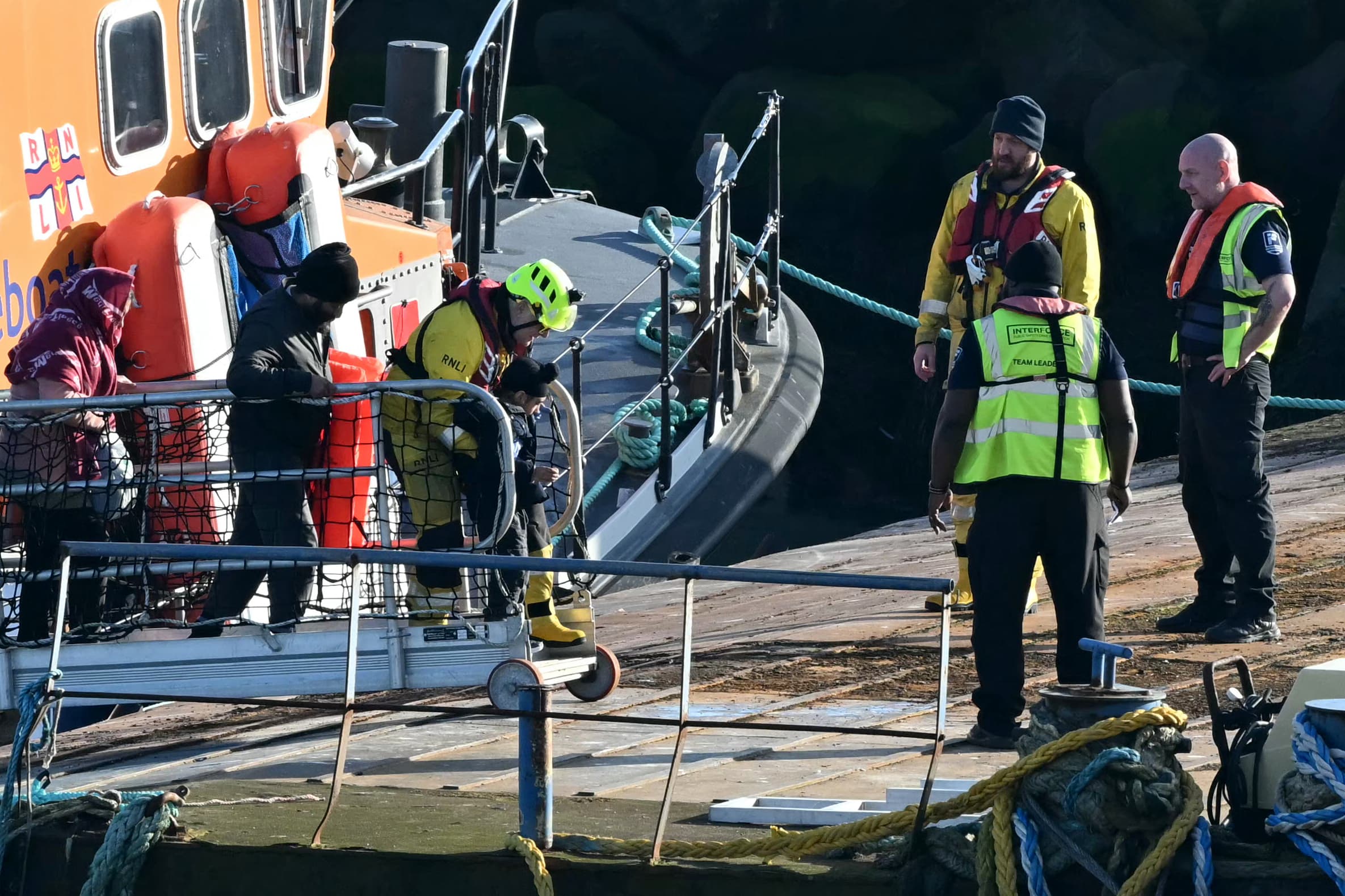 Migrants including children picked up at sea while attempting to cross the English Channel, are escorted off a National Lifeboat Institution (RNLI) Lifeboat upon arrival in Ramsgate, southeast England, on February 25, 2026. (AFP)