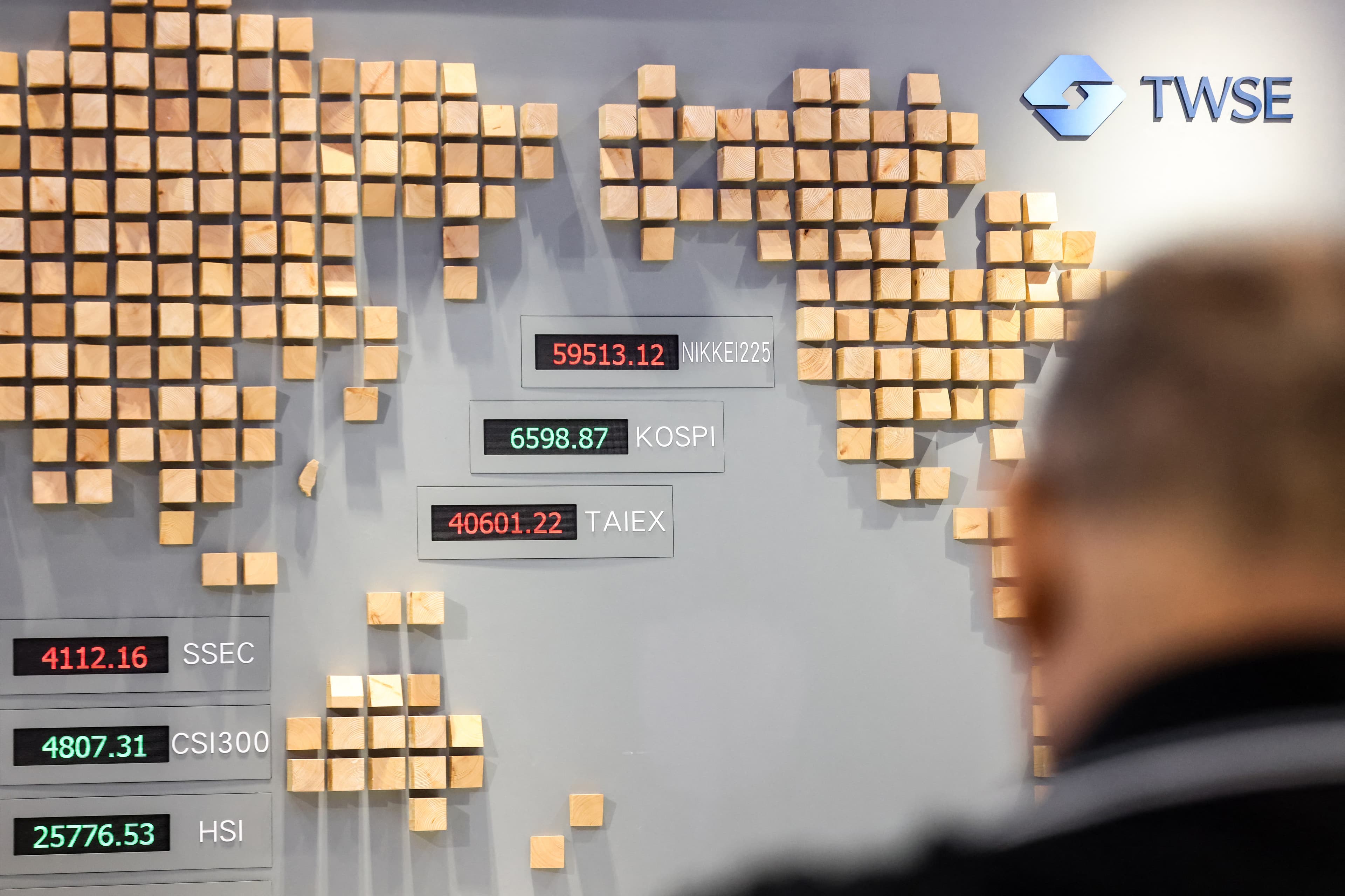 A man walks past a board showing numbers of the TAIEX Index (C) and other markets at the Taiwan Stock Exchange in Taipei on May 4, 2026. (Photo by I-Hwa Cheng / AFP)