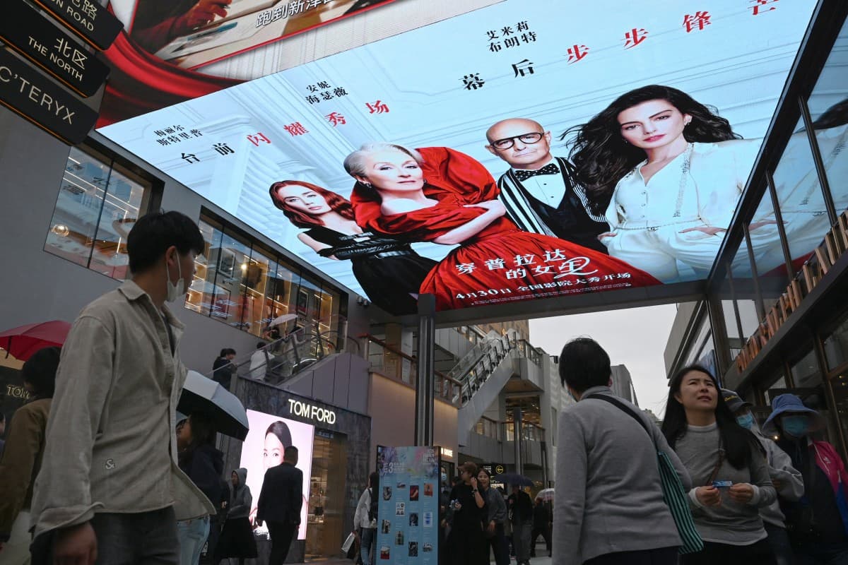 People walk below an electronic billboard advertising the movie "The Devil Wears Prada 2" at a shopping mall in Beijing on May 2, 2026, on the second day of a five-day national May Day holiday. (AFP)