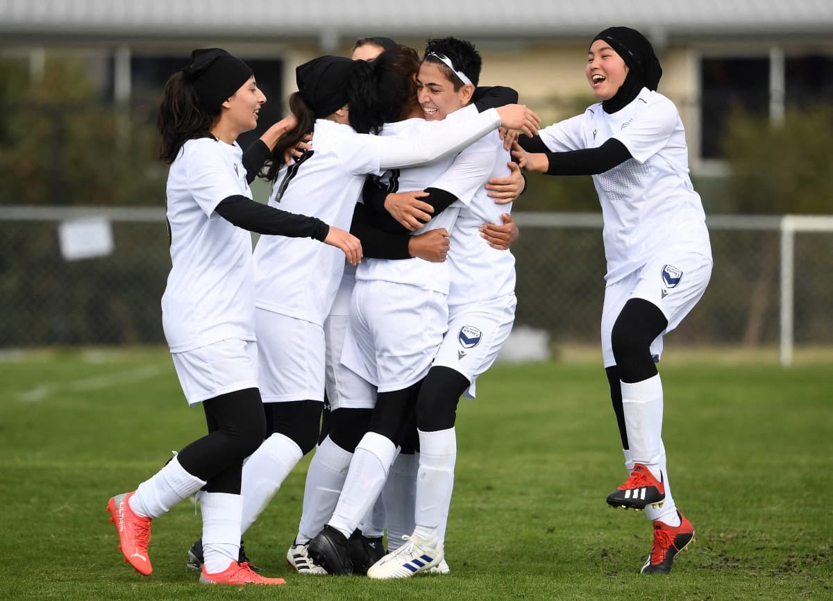 Members of the Afghanistan's national women's football team playing under the Melbourne Victory Afghan women’s team banner celebrate a goal in their first match in a local league against ETA Buffalo SC in Melbourne on April 24, 2022.