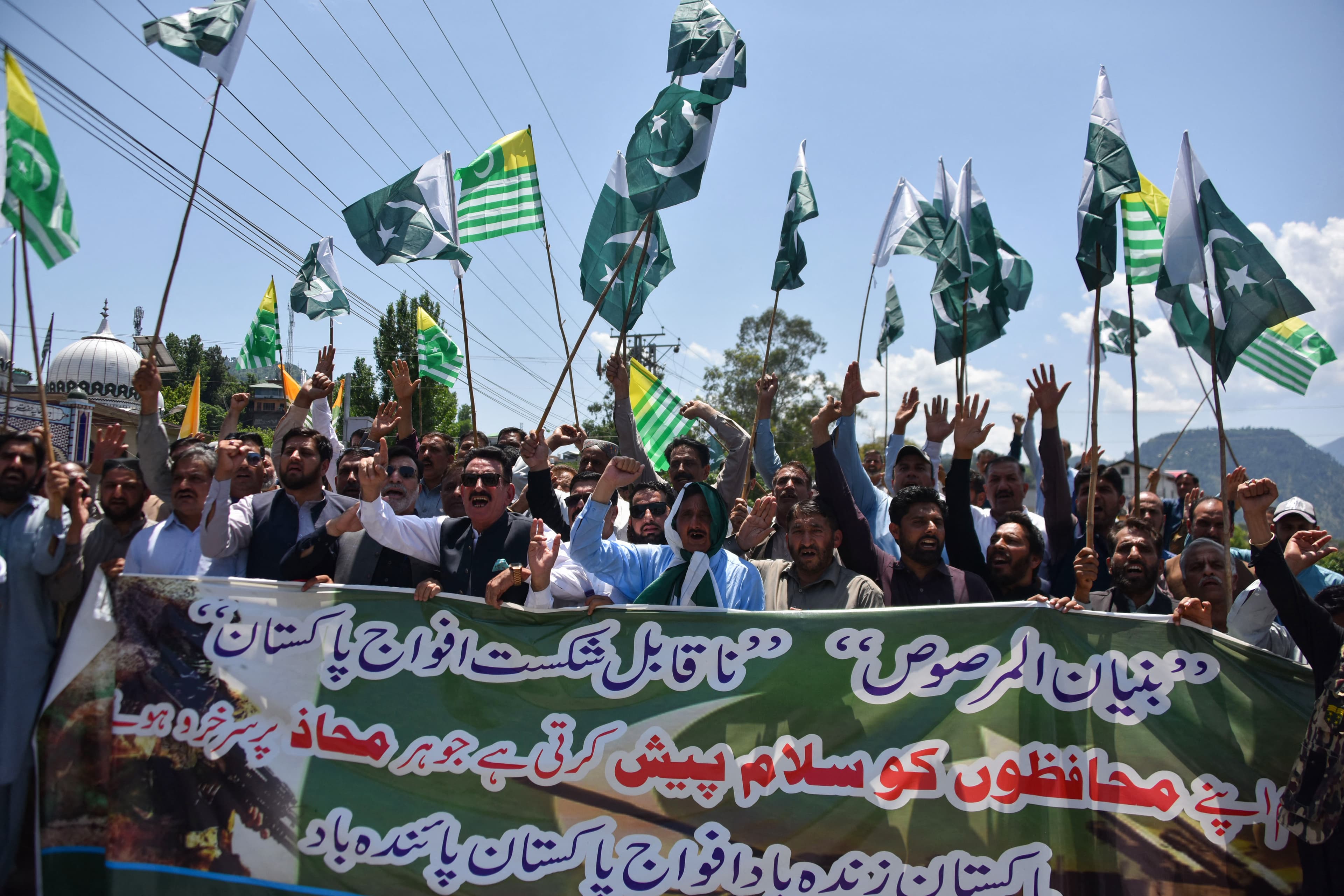Members of the Forest Department wave Kashmiri and Pakistani flags during a rally in Muzaffarabad on May 12, 2025, after a Pakistan-India ceasefire. (AFP/Sajjad Qayyum)