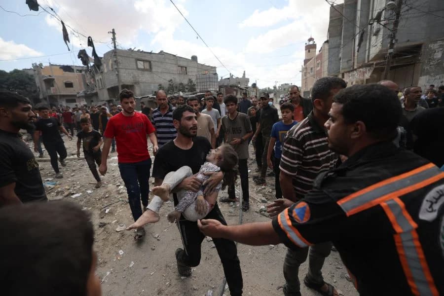 TOPSHOT - A Palestinian man rushes with a child in his arms to a waiting vehicle following an Israeli airstrike on the Rafah, in the southern Gaza Strip on October 17, 2023 (File photo by MOHAMMED ABED / AFP)