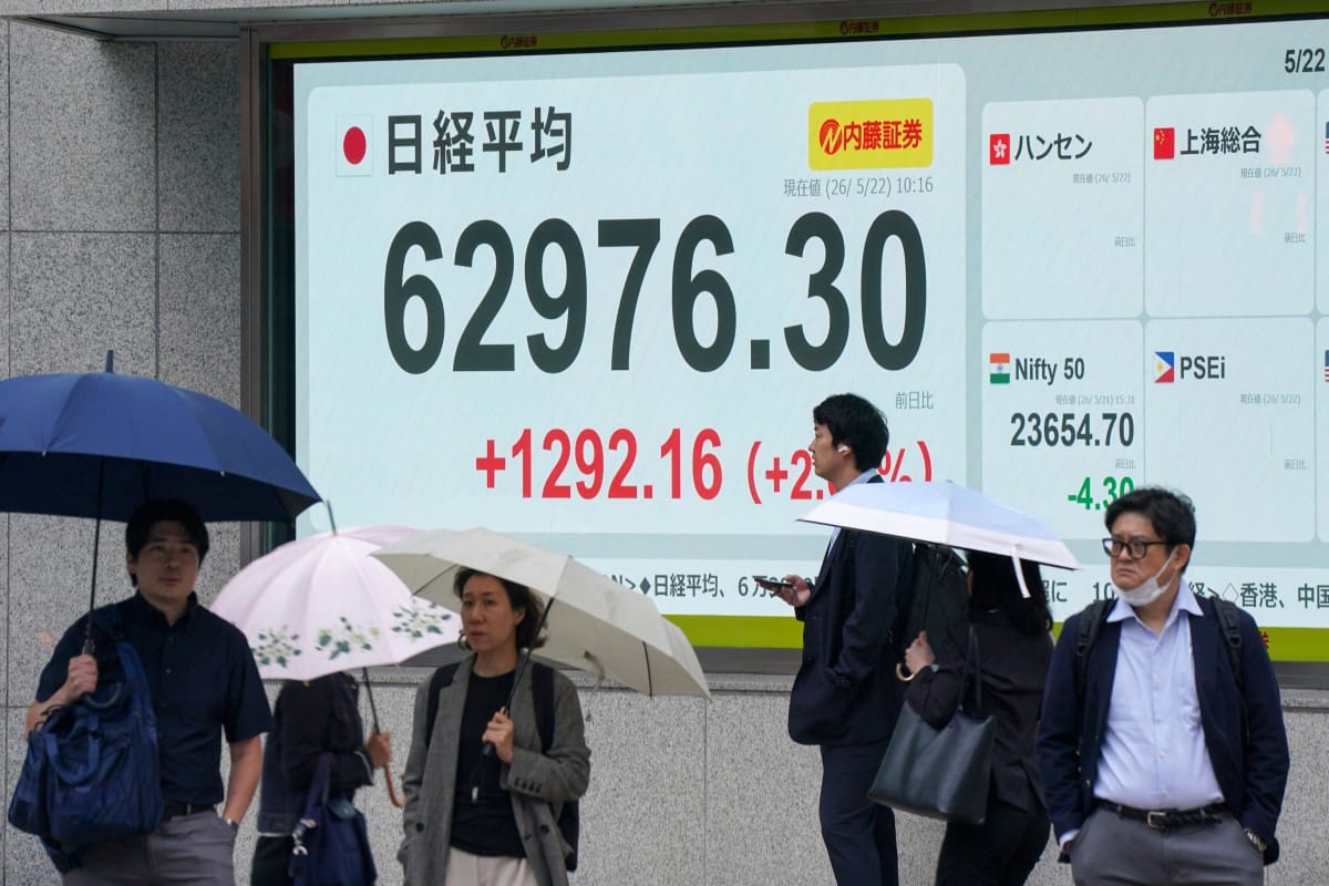 Pedestrians are pictured in front of an electronic quotation boards displaying the Nikkei Stock Average on the Tokyo Stock Exchange along a street in Tokyo on May 22, 2026. (Photo by Kazuhiro NOGI / AFP)