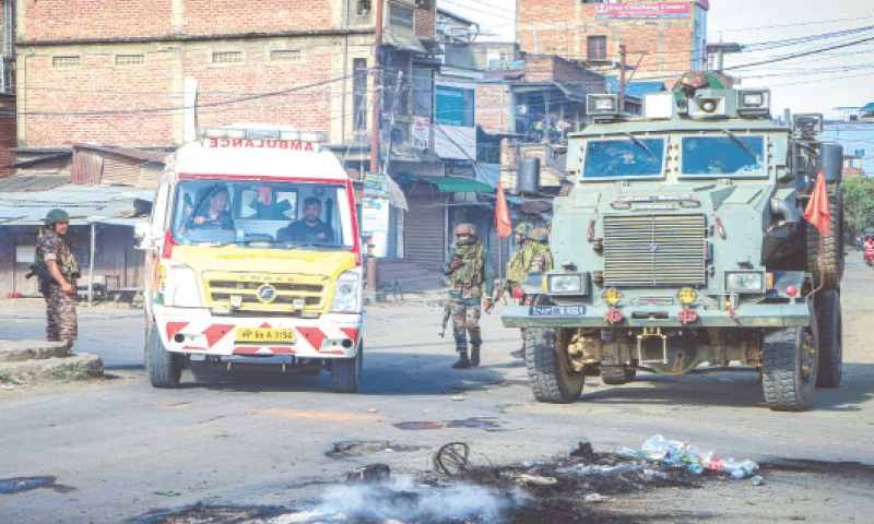 An ambulance rides past a security vehicle positioned in the middle of a road, during a curfew in Imphal on June 9, 2025. Riven by ethnic tensions, Manipur in India's northeast imposed an internet shutdown and curfew after protesters clashed with security