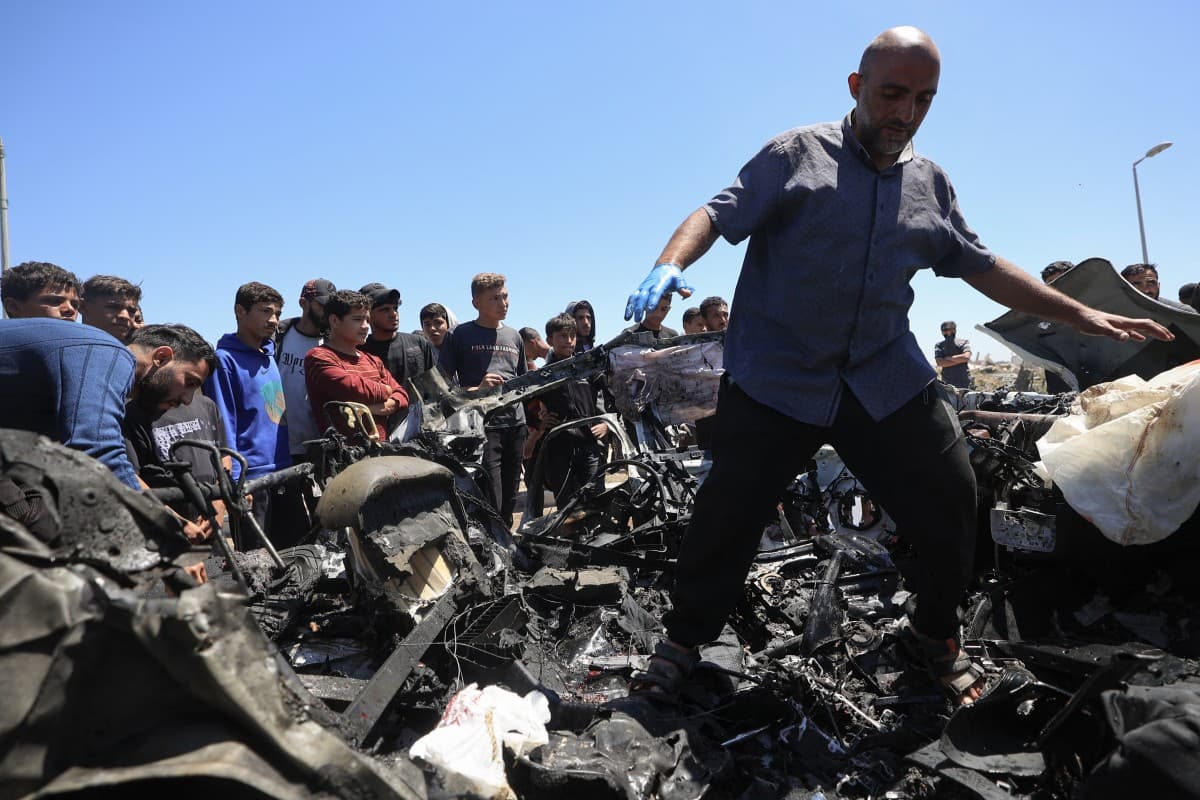 People inspect a destroyed civilian vehicle after it was targeted by an Israeli airstrike that reportedly killed three people on Salah al-Din Street, south of Bureij camp for Palestinian refugees in the central Gaza Strip on April 23, 2026. (AFP)