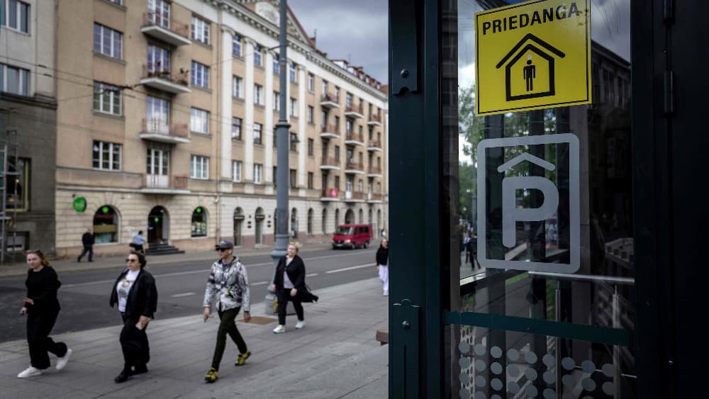 People pass the entrance to an underground car park marked as a shelter with a yellow sticker reading 'Priedanga' (Shelter) on Gediminas Prospect in central Vilnius on May 28, 2026. (AFP)