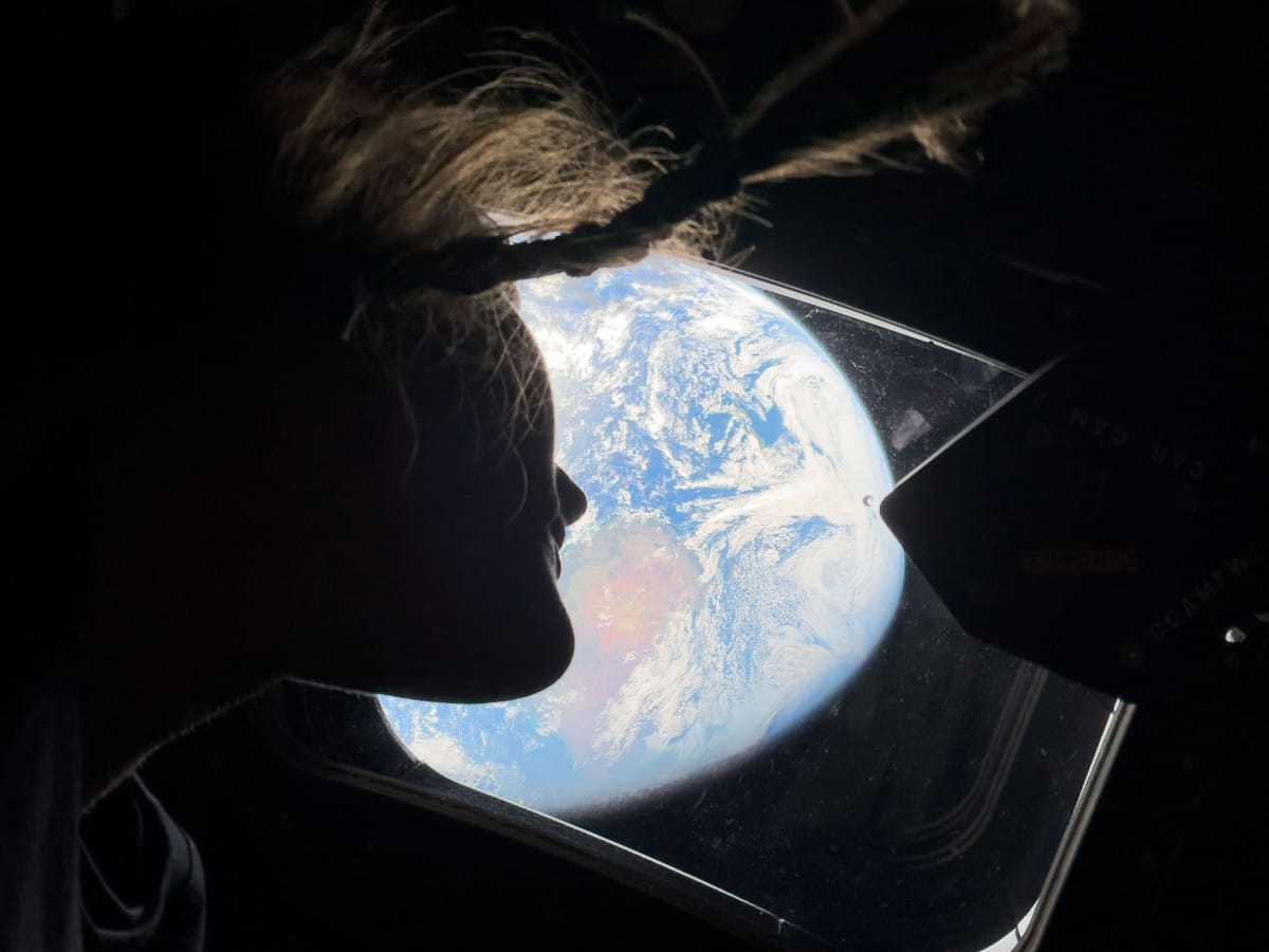 In this handout image provided by NASA, NASA astronaut and Artemis II mission specialist Christina Koch peers out of one of the Orion spacecraft's main cabin windows, looking back at Earth, as the crew travels towards the Moon on April 4, 2026. (IN SPACE/